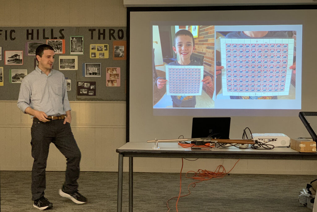 Alex Haimann shows his son Winston holding a pane of replica Inverted Jenny stamps at the August 8 Omaha Philatelic Society meeting